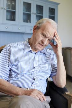 Senior Man Sitting In Chair At Home Suffering From Depression