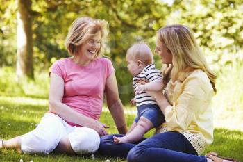 Grandmother And Mother Playing With Baby Son Outdoors In Garden