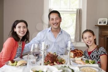 Jewish family at Shabbat dinner table smiling to camera