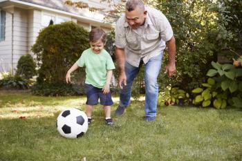 Grandfather Playing Soccer In Garden With Grandson