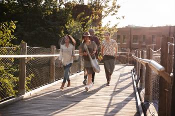 Group Of Friends Walking Along Bridge In Urban Setting