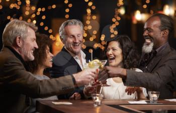 Group Of Middle Aged Friends Celebrating In Bar Together