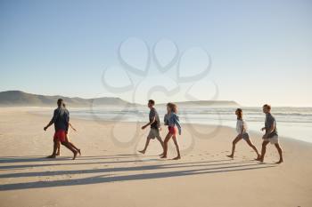Group Of Friends On Vacation Walking Along Beach Together