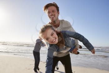 Father With Children Having Fun On Winter Beach Together