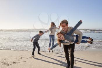 Parents With Children Having Fun On Winter Beach Together
