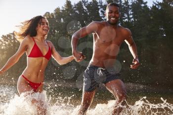 Young mixed race couple running and splashing in a lake
