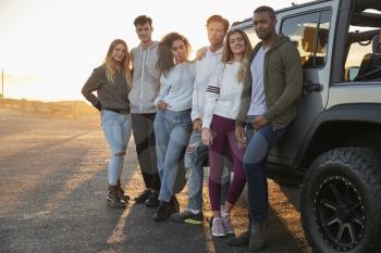Young adult friends on a road trip standing by their jeep