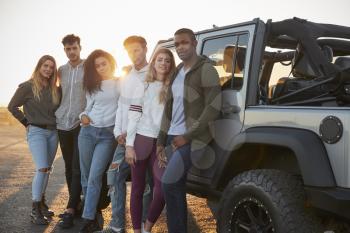 Young adult friends on a road trip standing by their jeep