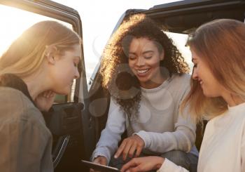 Female friends planning road trip route with tablet computer