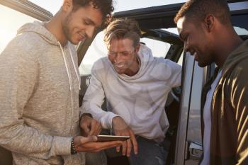 Male friends planning road trip route with tablet computer