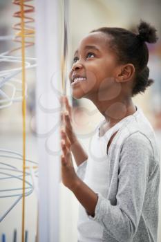 Young black girl looking at a science exhibit, vertical