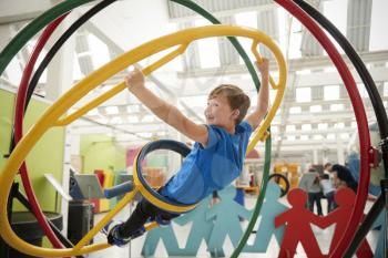Schoolboy in science centre using human gyroscope, side view
