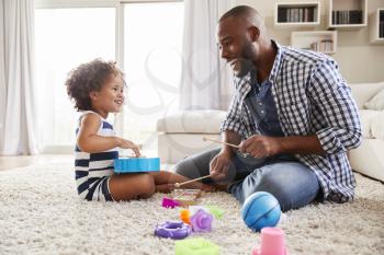 Young black father playing with daughter in the sitting room