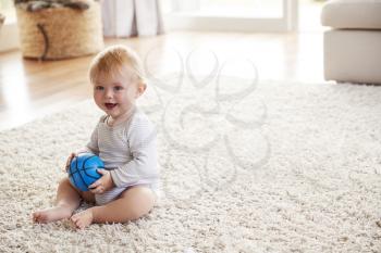 White toddler boy sitting on the floor in sitting room