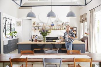 Woman leaning on island in an open plan kitchen dining room