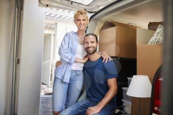 Portrait Of Couple Sitting In Back Of Removal Truck On Moving Day