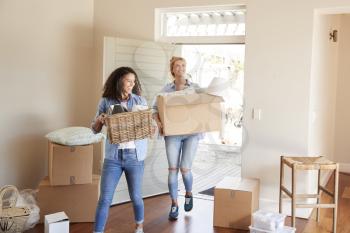 Female Friends Carrying Boxes Into New Home On Moving Day