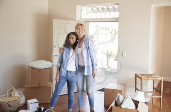 Female Friends Standing In Lounge Of New Home On Moving Day