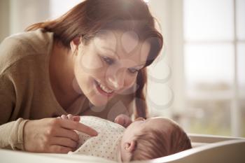 Mother Playing With Newborn Baby Lying On Changing Table