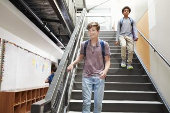 High School Students Walking Down Stairs In Busy College Building