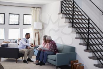 Senior Couple Meeting With Male Financial Advisor At Home