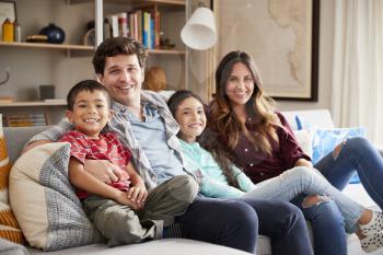 Portrait Of Happy Family Relaxing On Sofa At Home Together