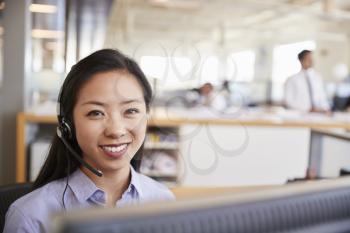 Young Asian woman working in a call centre smiling to camera