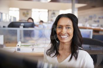 Young mixed race woman in a call centre looking to camera
