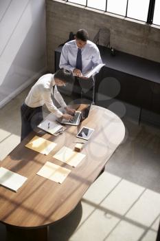 Two businessmen stand working at a desk in an office