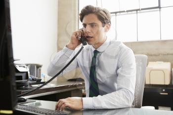 Young white businessman on the phone at an office desk