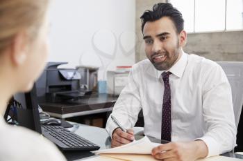 Young Hispanic male professional in meeting with woman in office