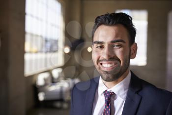 Young Hispanic businessman smiling to camera, close up