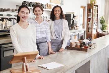 Three female coffee shop owners standing behind the counter