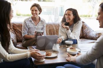 Four female friends talking over coffee at a coffee shop