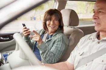 Woman passenger using GPS on smartphone in a car pointing