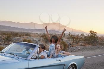 Group Of Friends On Road Trip Driving Classic Convertible Car