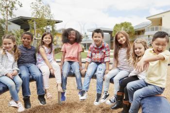 Elementary school kids sitting on carousel in the schoolyard
