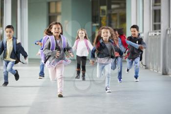 Young school kids running in a corridor in their school, close up