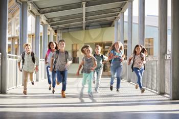 School kids running in elementary school corridor, close up