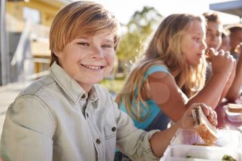 Boy at elementary school lunch table smiling to camera