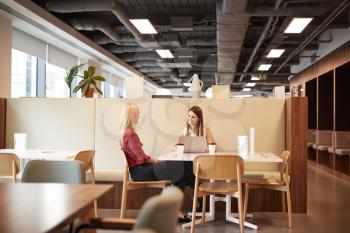 Two Young Businesswomen Having Informal Interview In Cafeteria Area At Graduate Recruitment Assessment Day
