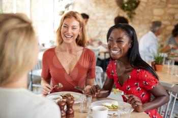 Young female friends smiling at brunch in a cafe, close up