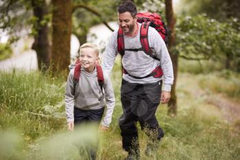 Pre-teen boy and his father hiking in a forest, selective focus