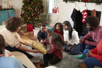 Mother Giving Daughter Gift As Multi Generation Family Celebrate Christmas At Home Together