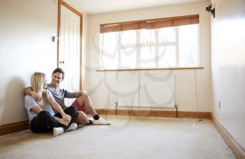 Couple Sitting On Floor In Empty Room Of New Home Planning Design