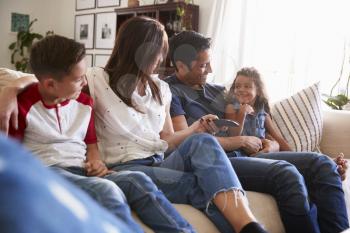 Young Hispanic family sitting on the sofa at home to watch TV, looking at each other, close up