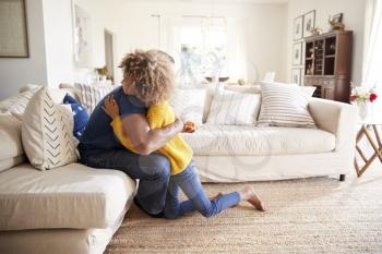 Pre-teen girl hugging her father in sitting room after giving him a handmade gift, side view