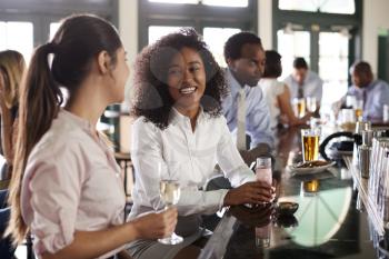 Two Businesswomen Meeting For After Works Drinks In Bar