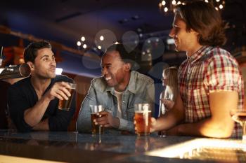 Group Of Male Friends Drinking Beer In Bar Together