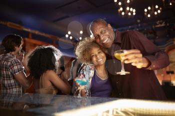 Portrait Of Senior Couple Drinking And Dancing In Bar Together